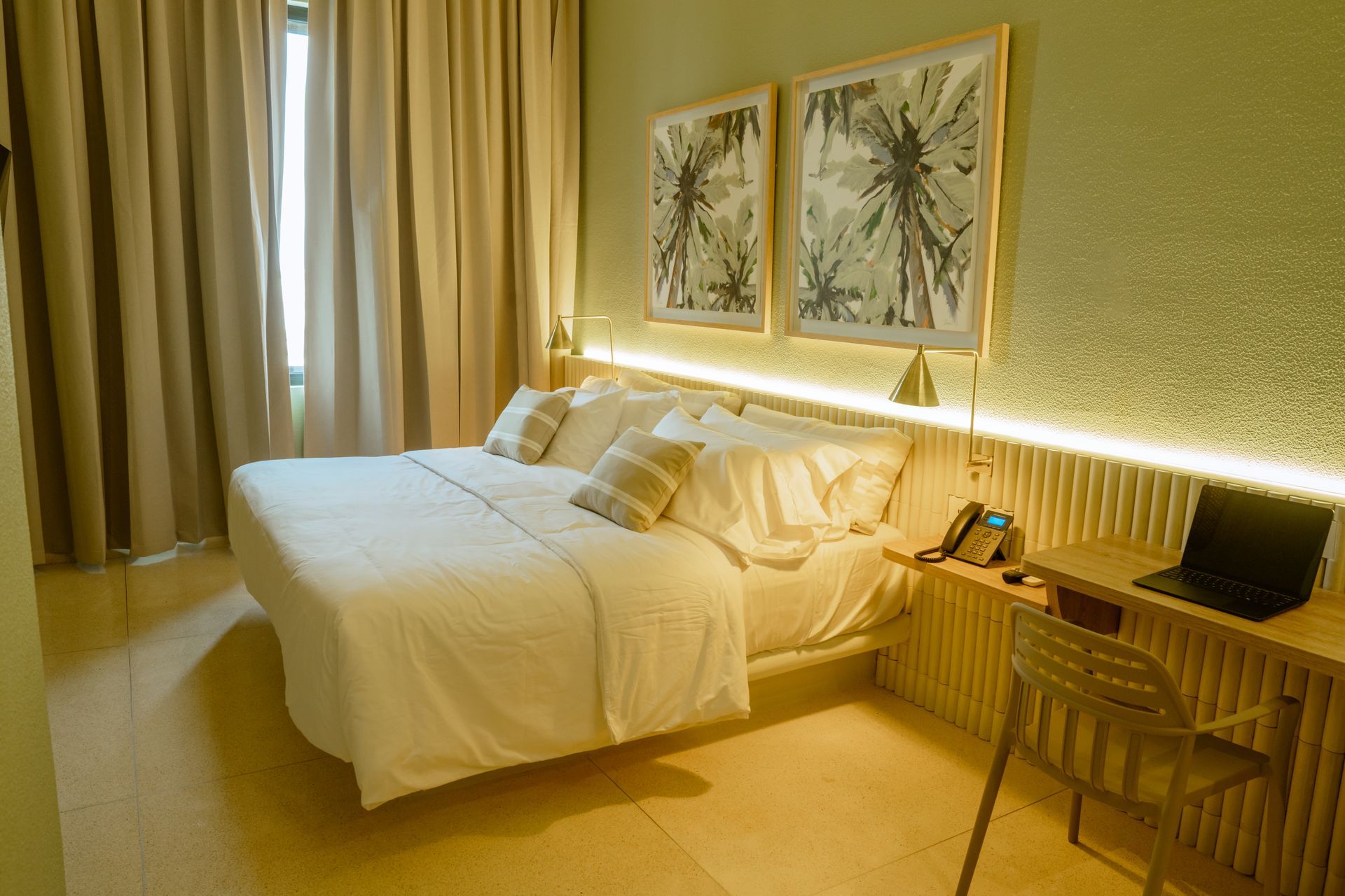 Una habitación de hotel con una cama, un escritorio, una silla y una computadora portátil.