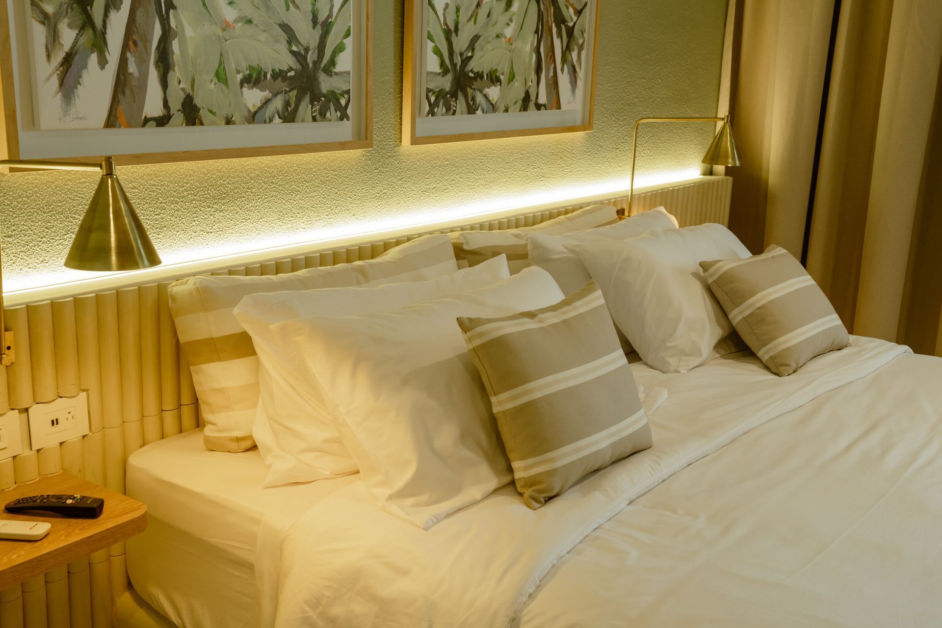 Una cama con sábanas blancas y almohadas en una habitación de hotel.