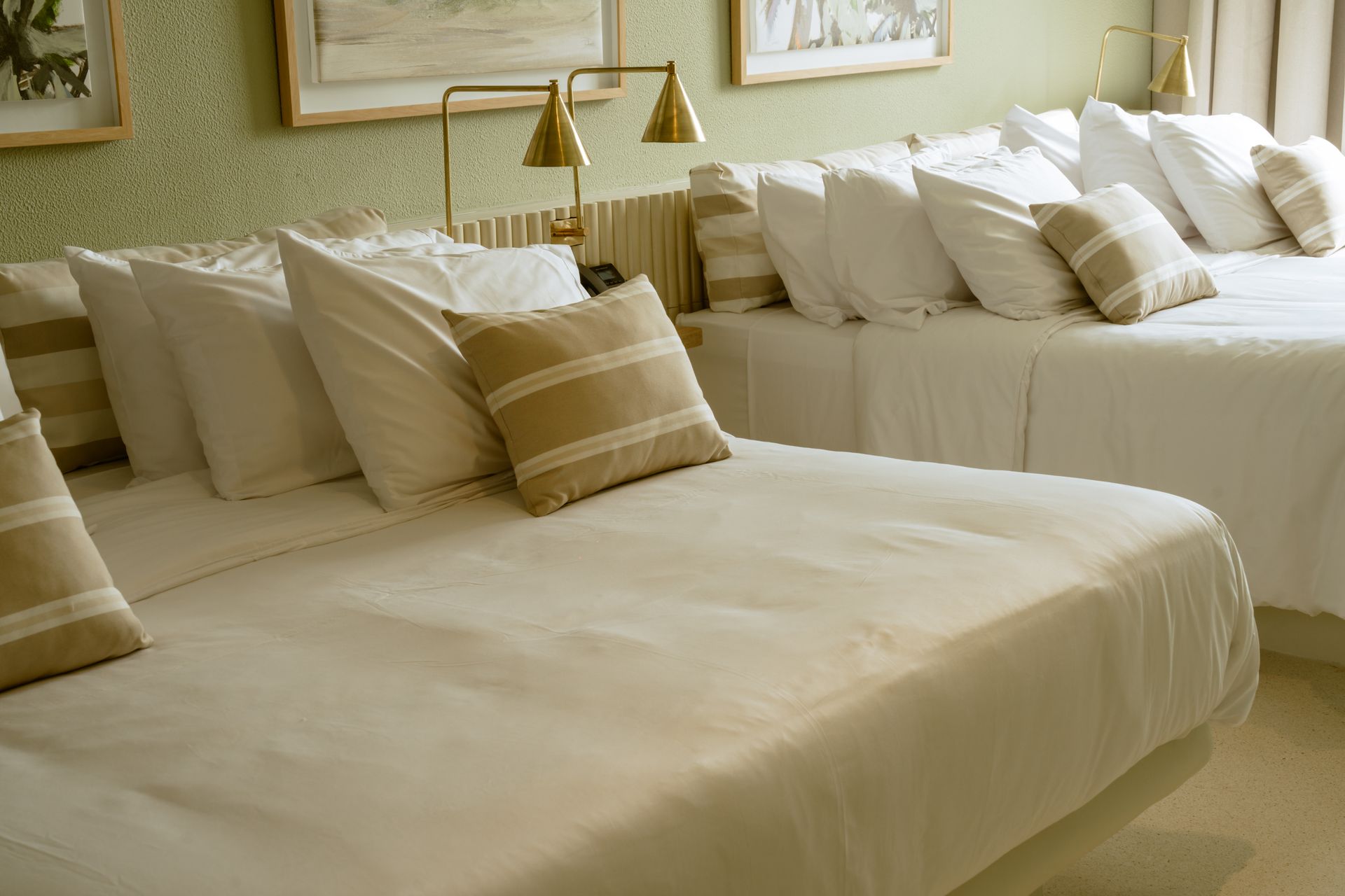 Dos camas en una habitación de hotel con sábanas y almohadas blancas.