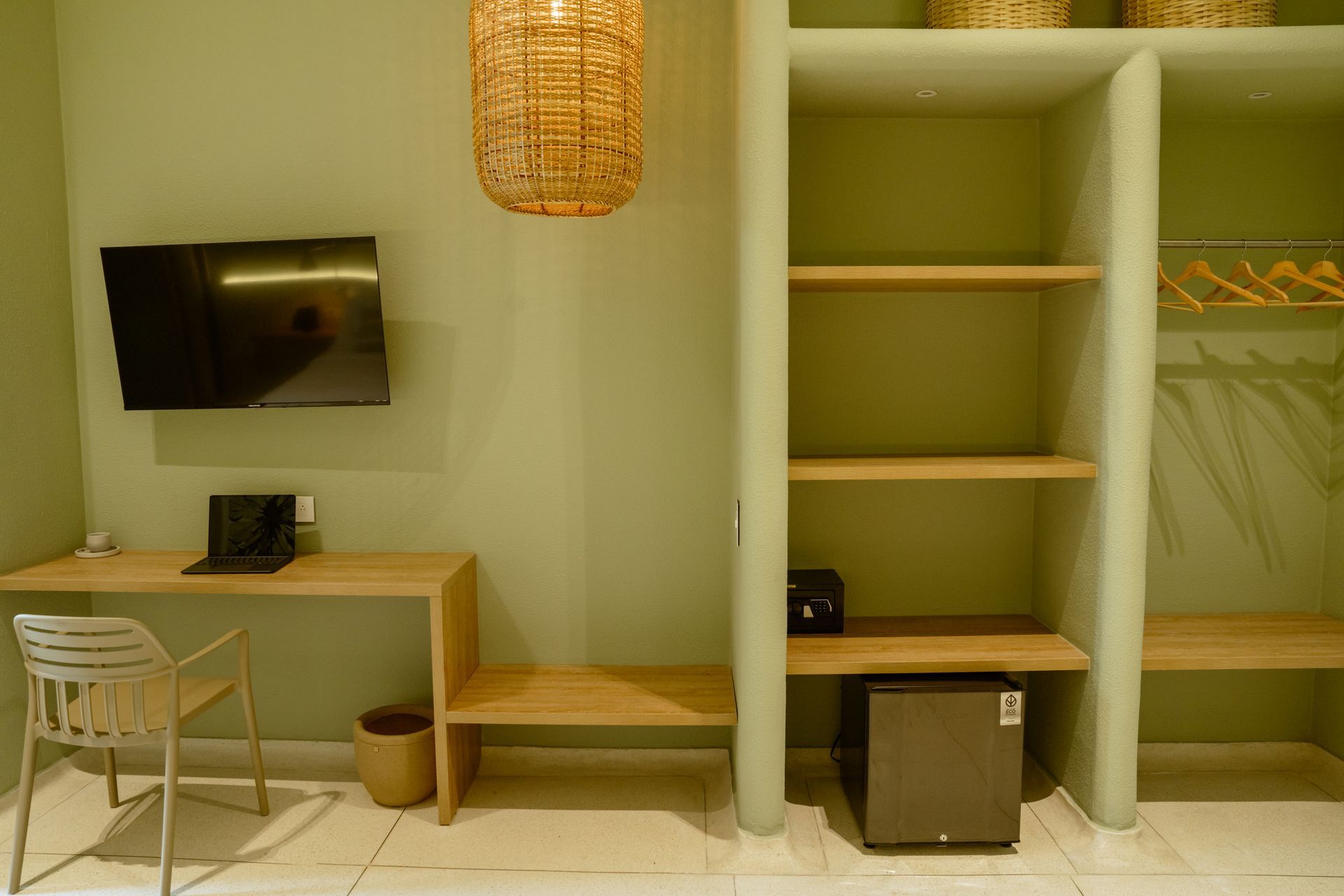 Una habitación de hotel con escritorio, silla, televisión y estantes.