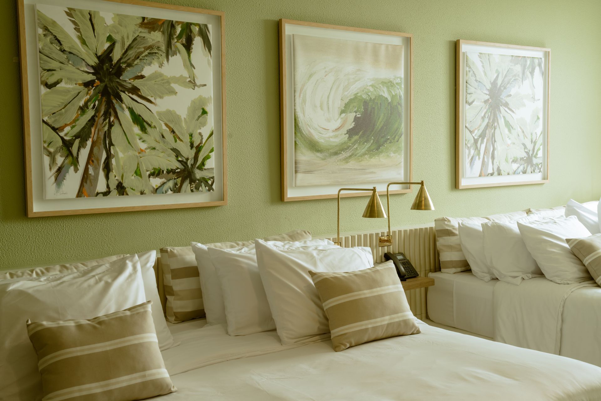 Una habitación de hotel con dos camas y dos cuadros en la pared.