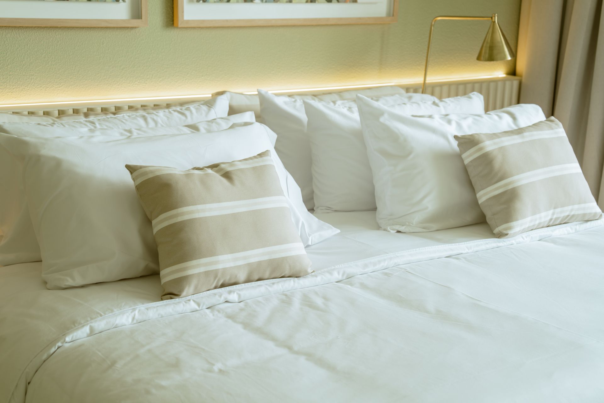 Una cama con sábanas blancas y almohadas en una habitación de hotel.