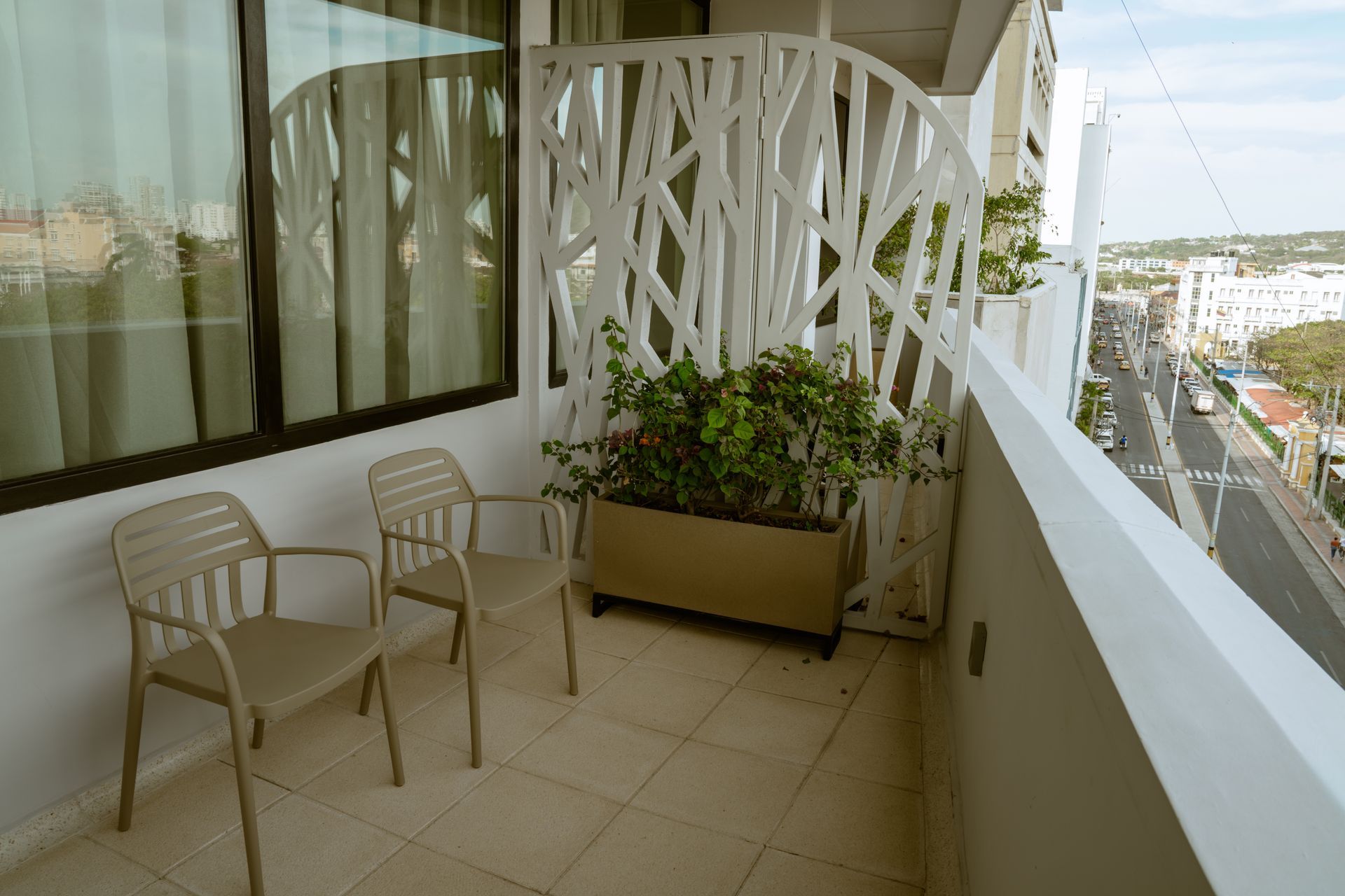 Un balcón con dos sillas y una planta en maceta.