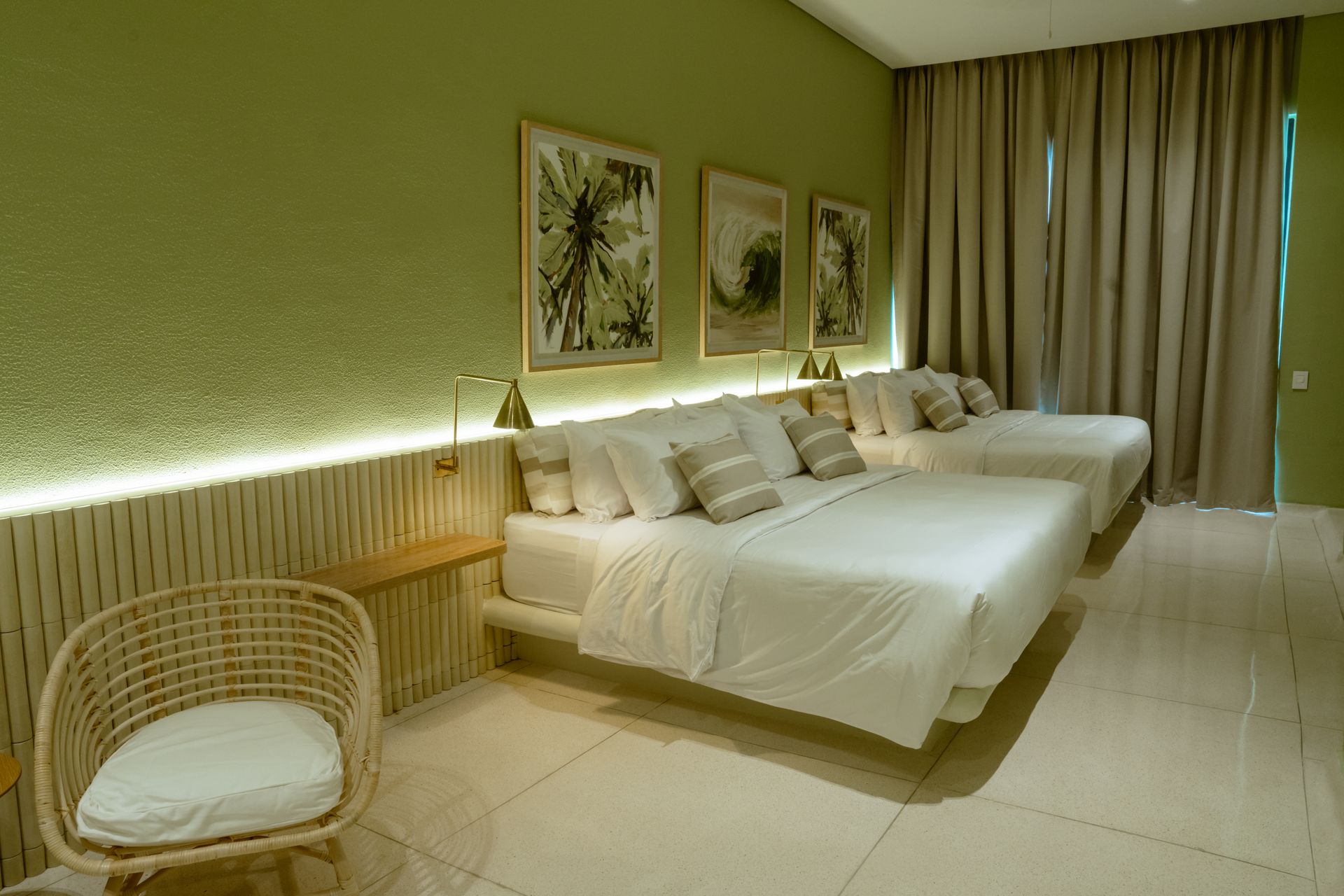 Una habitación de hotel con dos camas y una silla de mimbre.