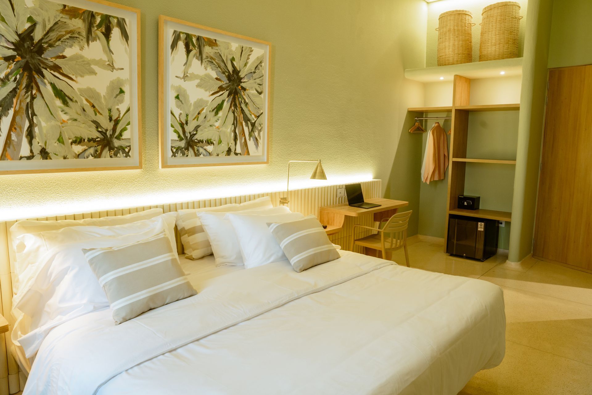 Una habitación de hotel con una cama, un escritorio, una silla y cuadros en la pared.