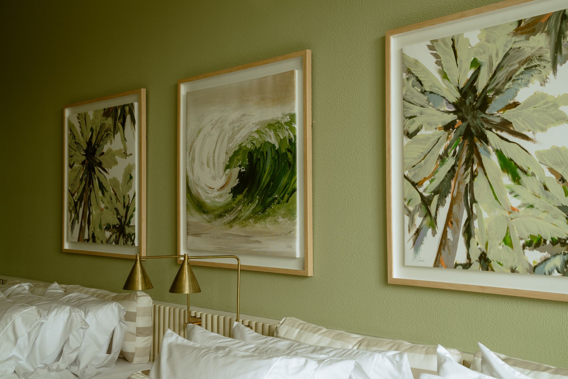 Tres cuadros están colgados en una pared encima de una cama.