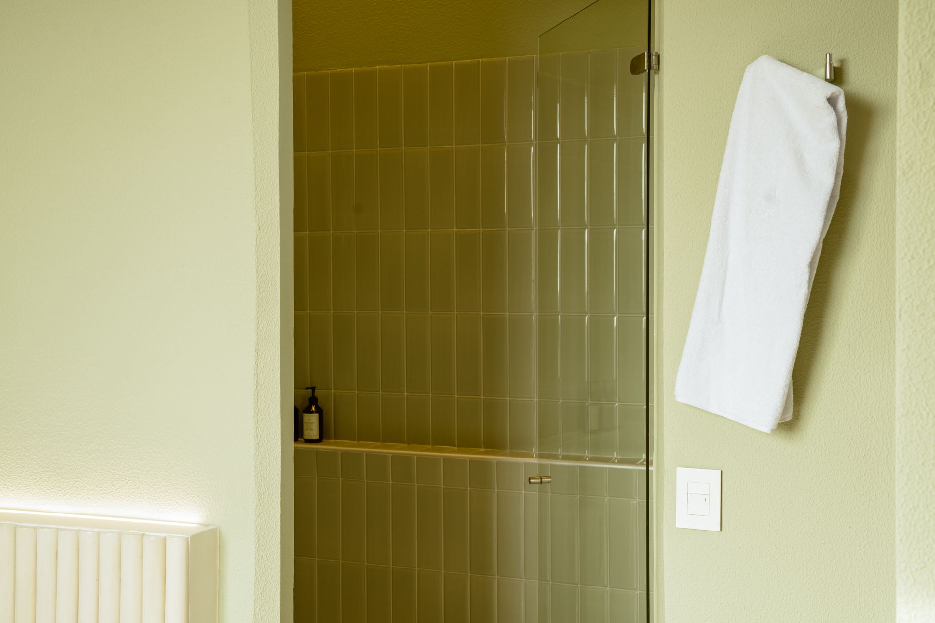 Un baño con una puerta de ducha de cristal y una toalla colgada en la pared.