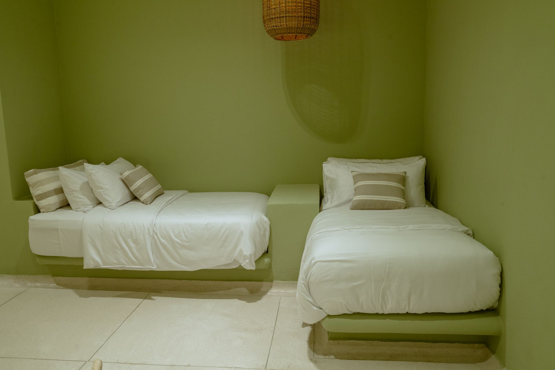 Dos camas están una al lado de la otra en una habitación con paredes verdes.