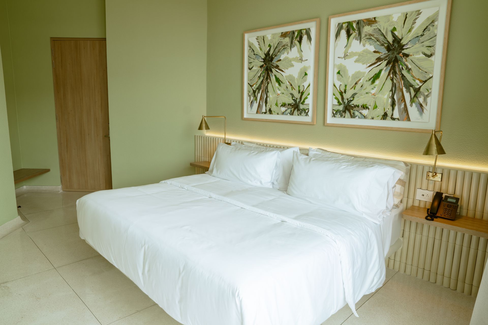 Una habitación de hotel con una cama tamaño king y dos cuadros en la pared.