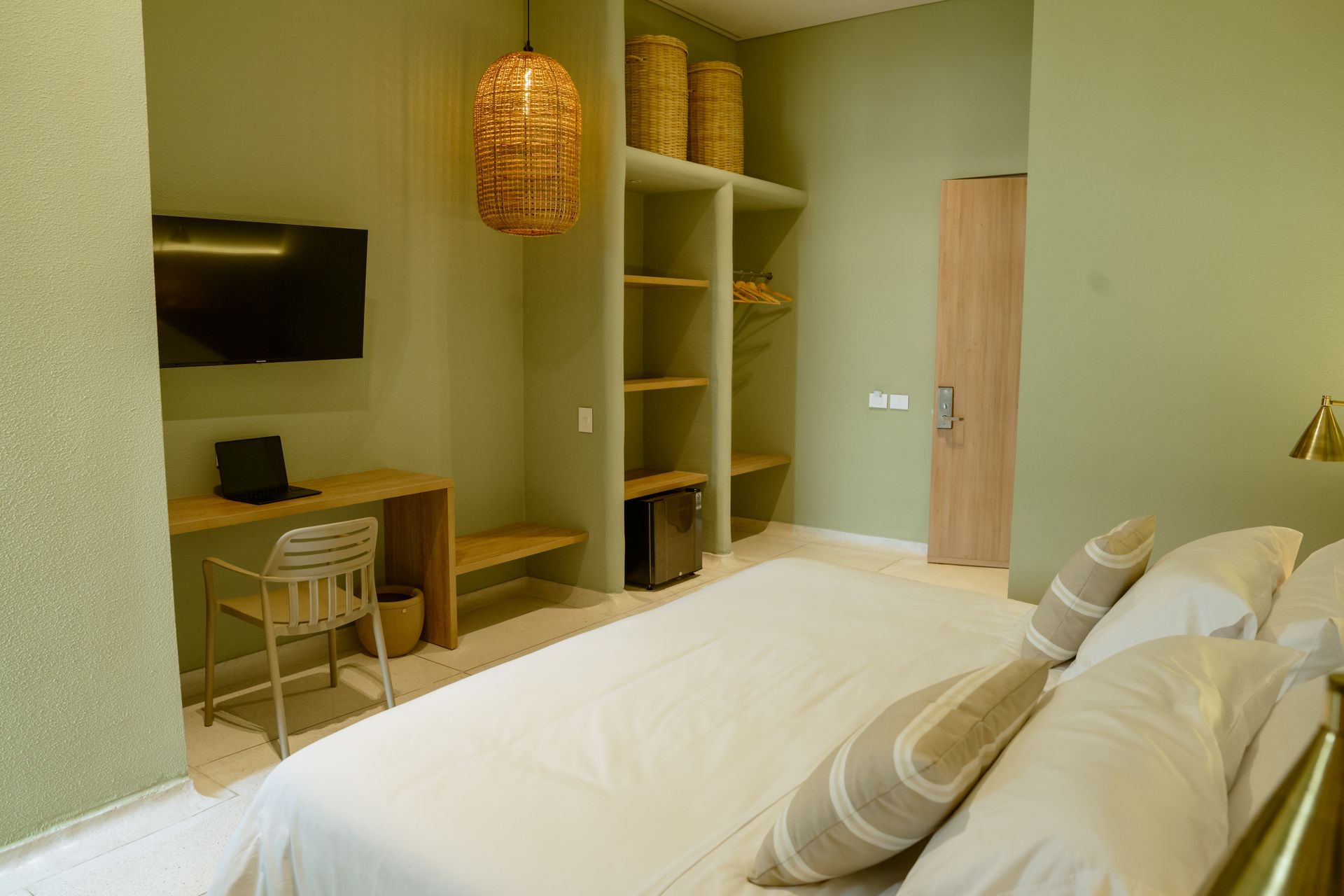 Una habitación de hotel con una cama grande, escritorio, silla y televisión.