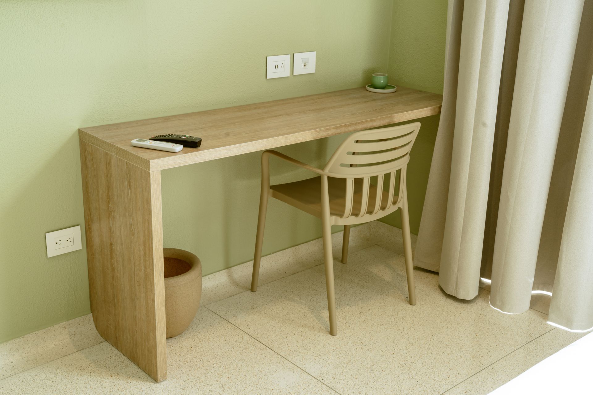 Un escritorio de madera con una silla en una habitación al lado de una ventana.
