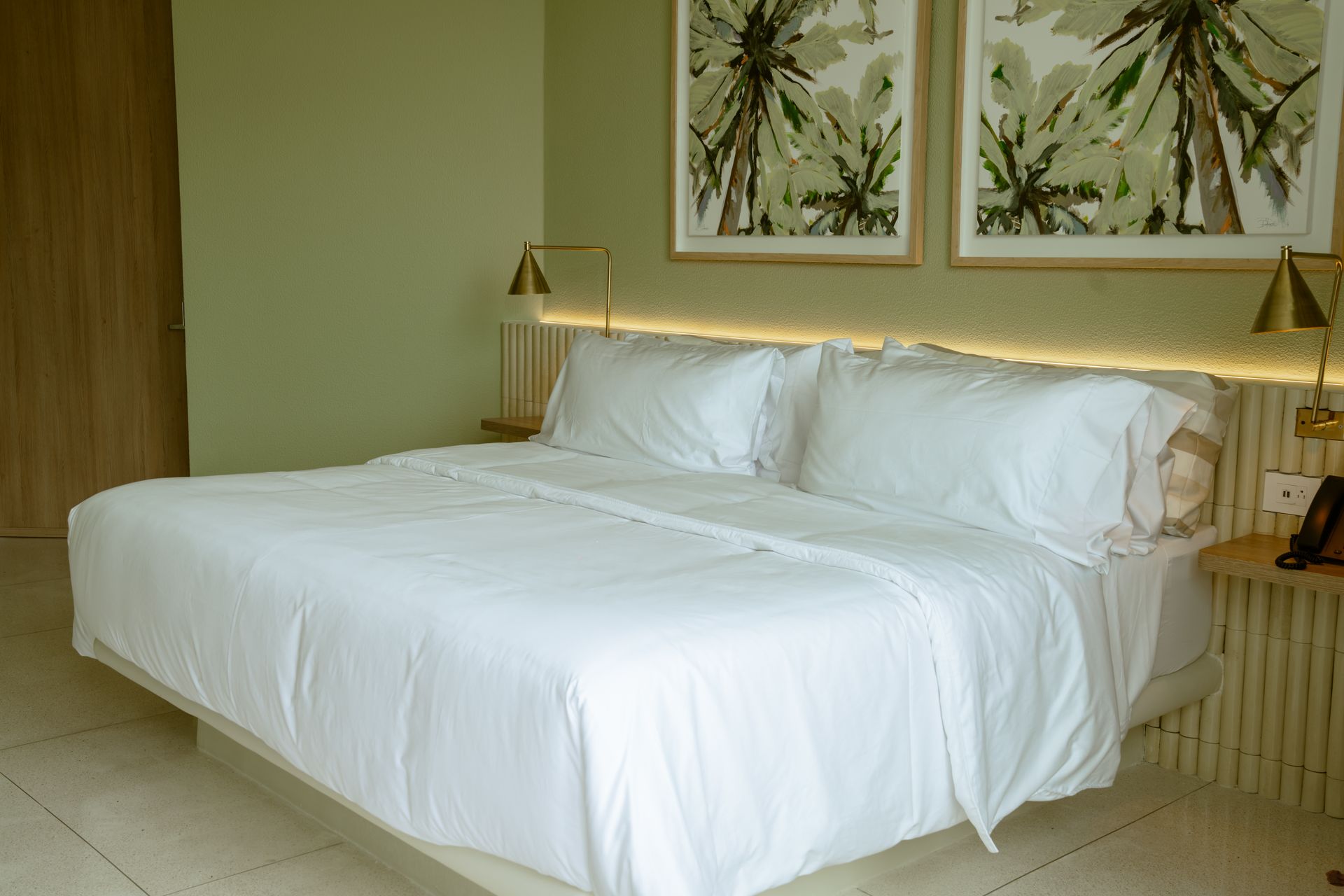 Una cama con sábanas blancas y almohadas en una habitación de hotel.