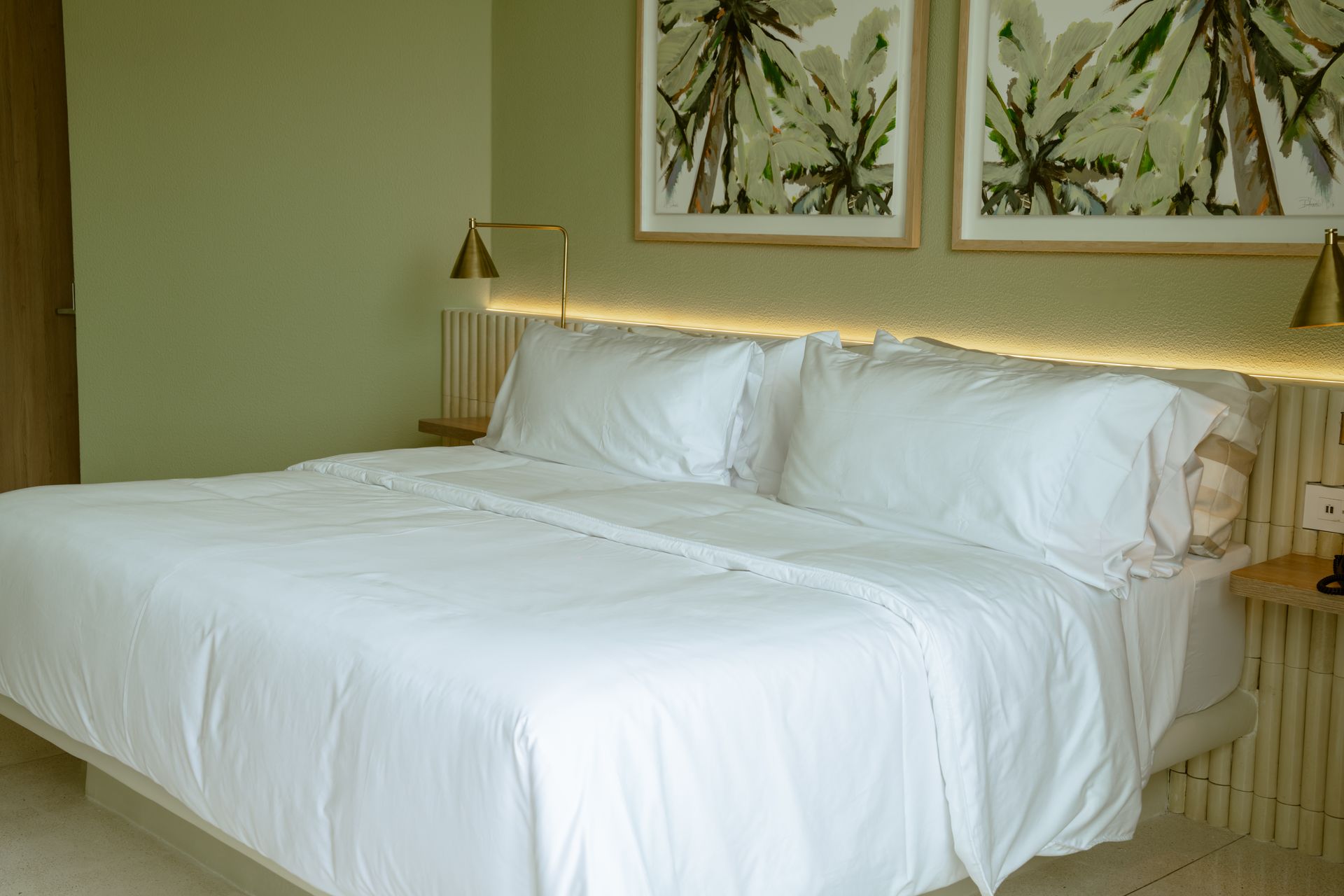 Una cama con sábanas blancas y almohadas en una habitación de hotel.