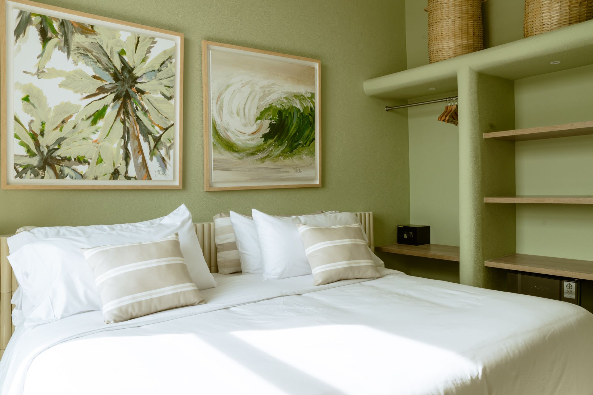 Un dormitorio con una cama, dos cuadros en la pared y estanterías.