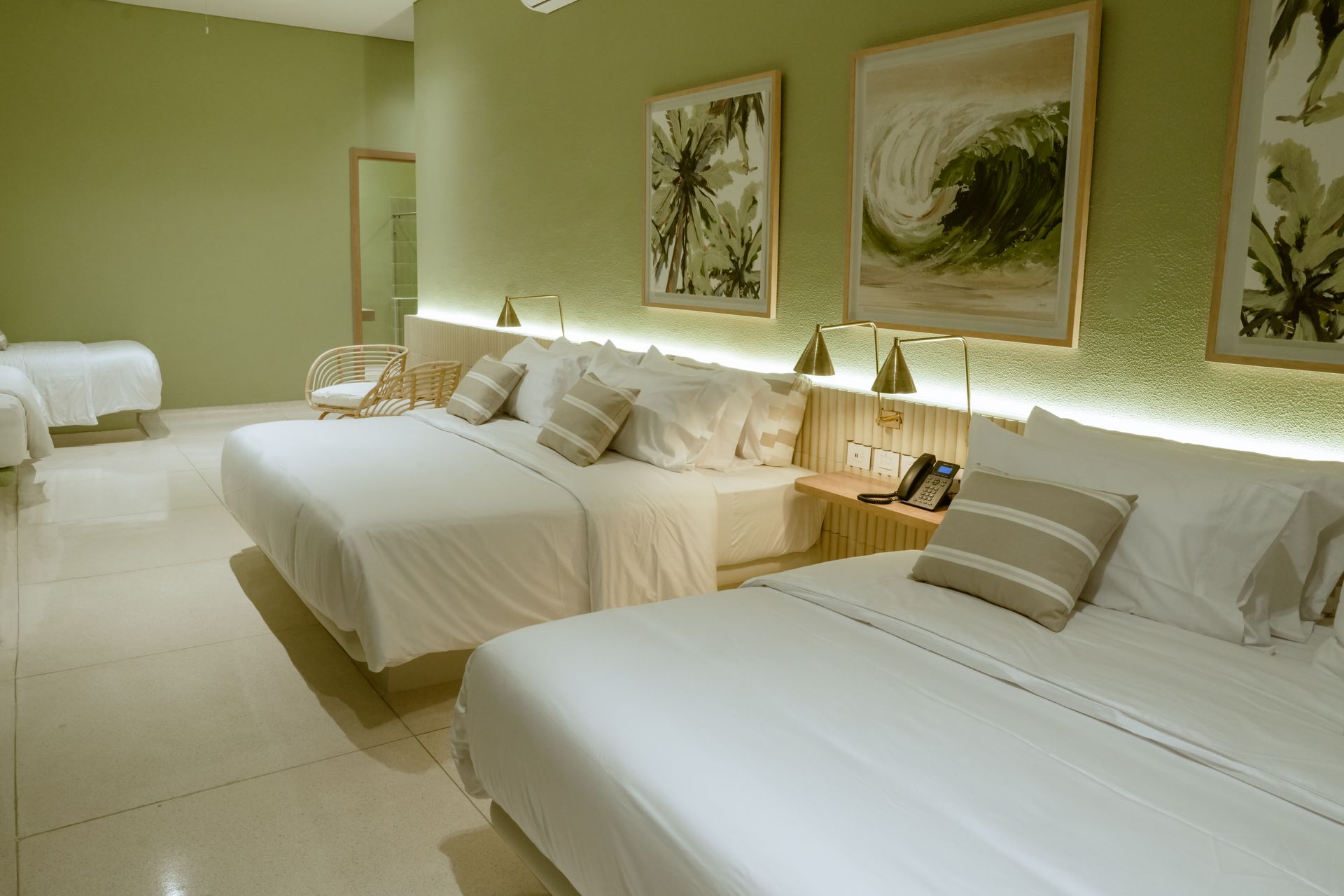 Una habitación de hotel con tres camas y dos cuadros en la pared.