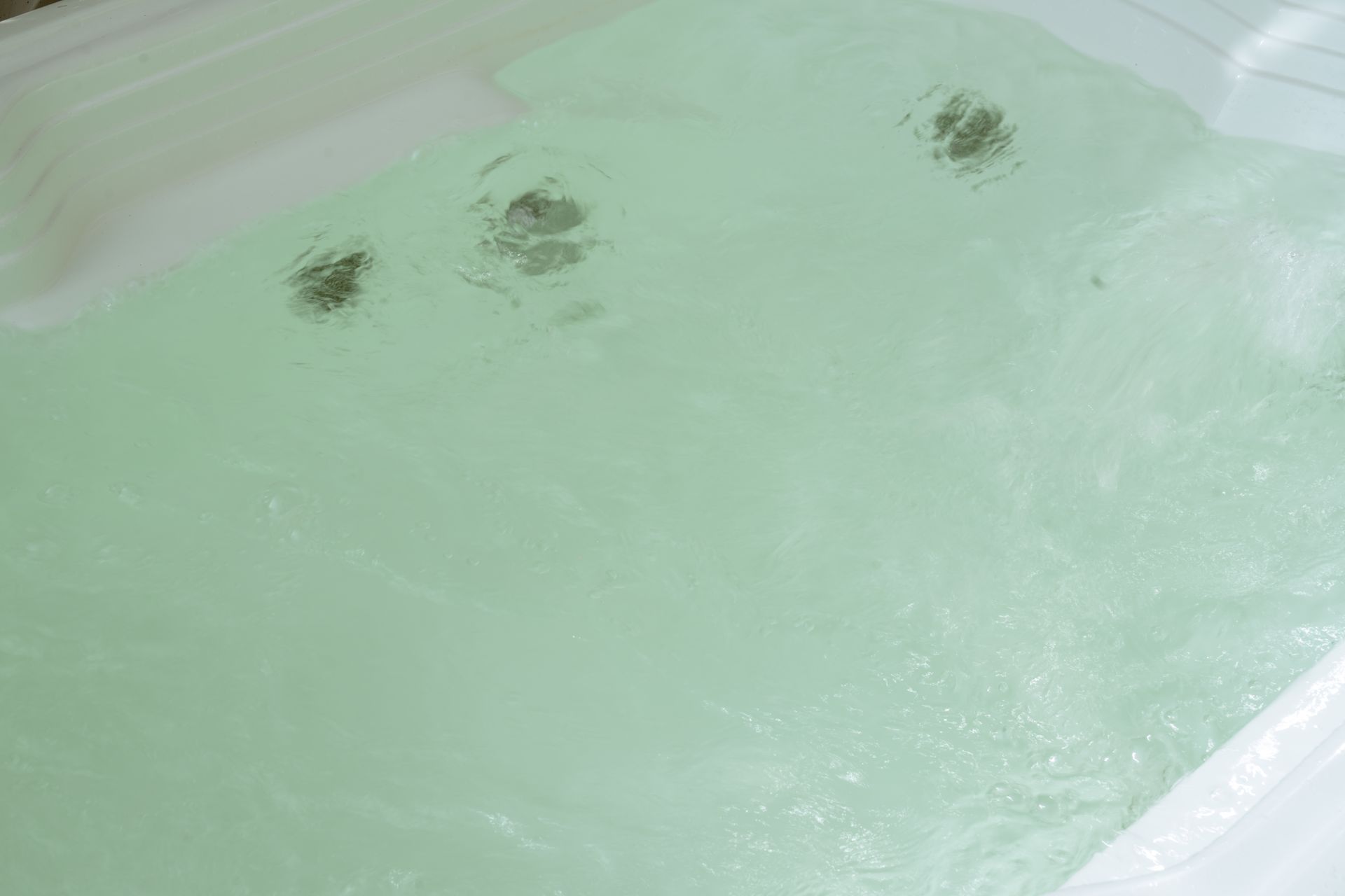 Una bañera llena de agua verde y burbujas.