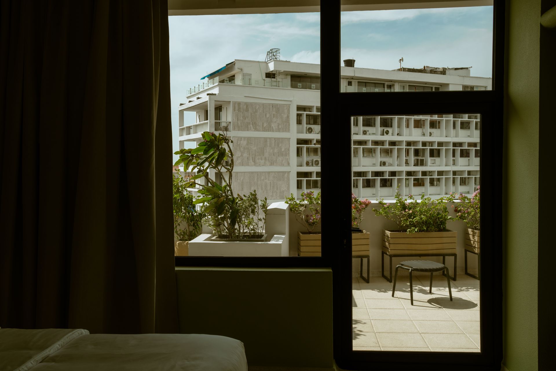 Un dormitorio con vista a un balcón y a un edificio a través de una ventana.