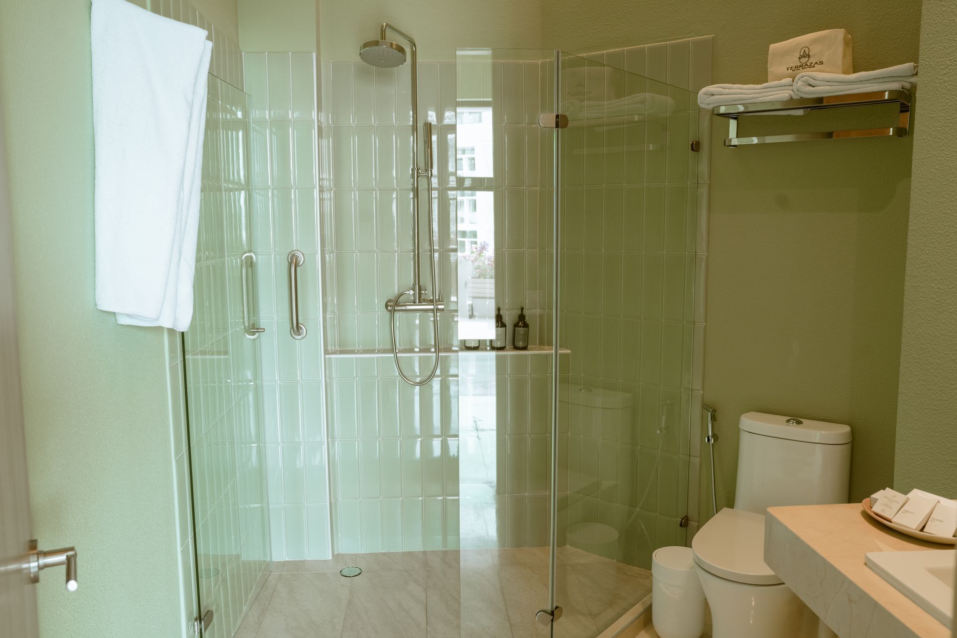 Un baño con inodoro, lavabo, ducha y puertas de cristal.