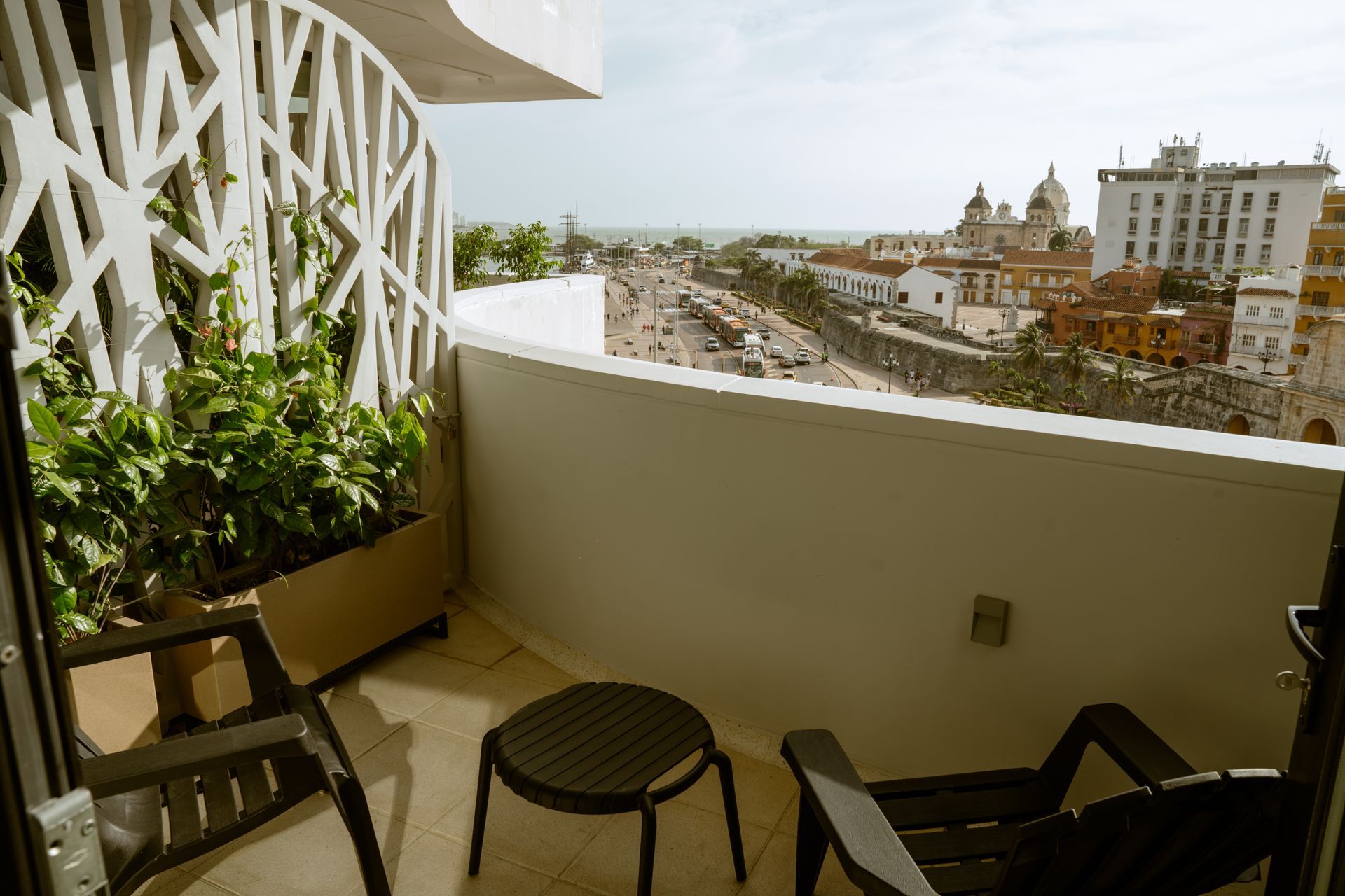 Un balcón con dos sillas y una mesa con vista a una ciudad.