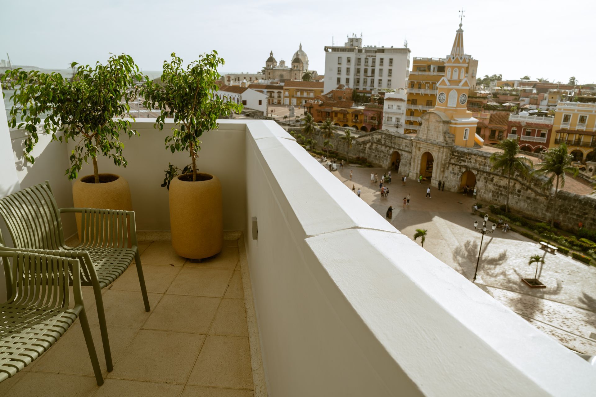 Un balcón con sillas y plantas en macetas con vistas a una ciudad.