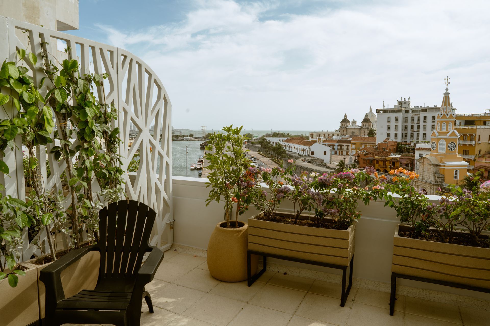 Un balcón con una silla y plantas en macetas y una vista de la ciudad.