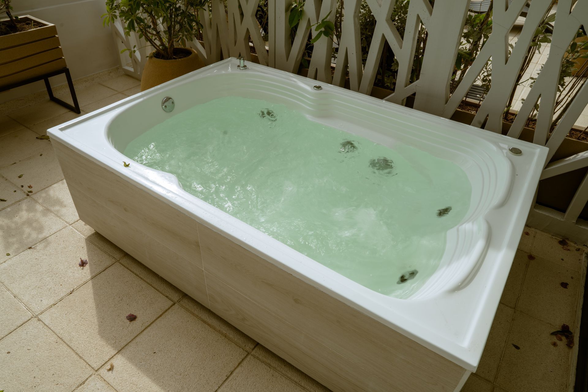 Una bañera llena de agua verde está colocada sobre un suelo de baldosas.