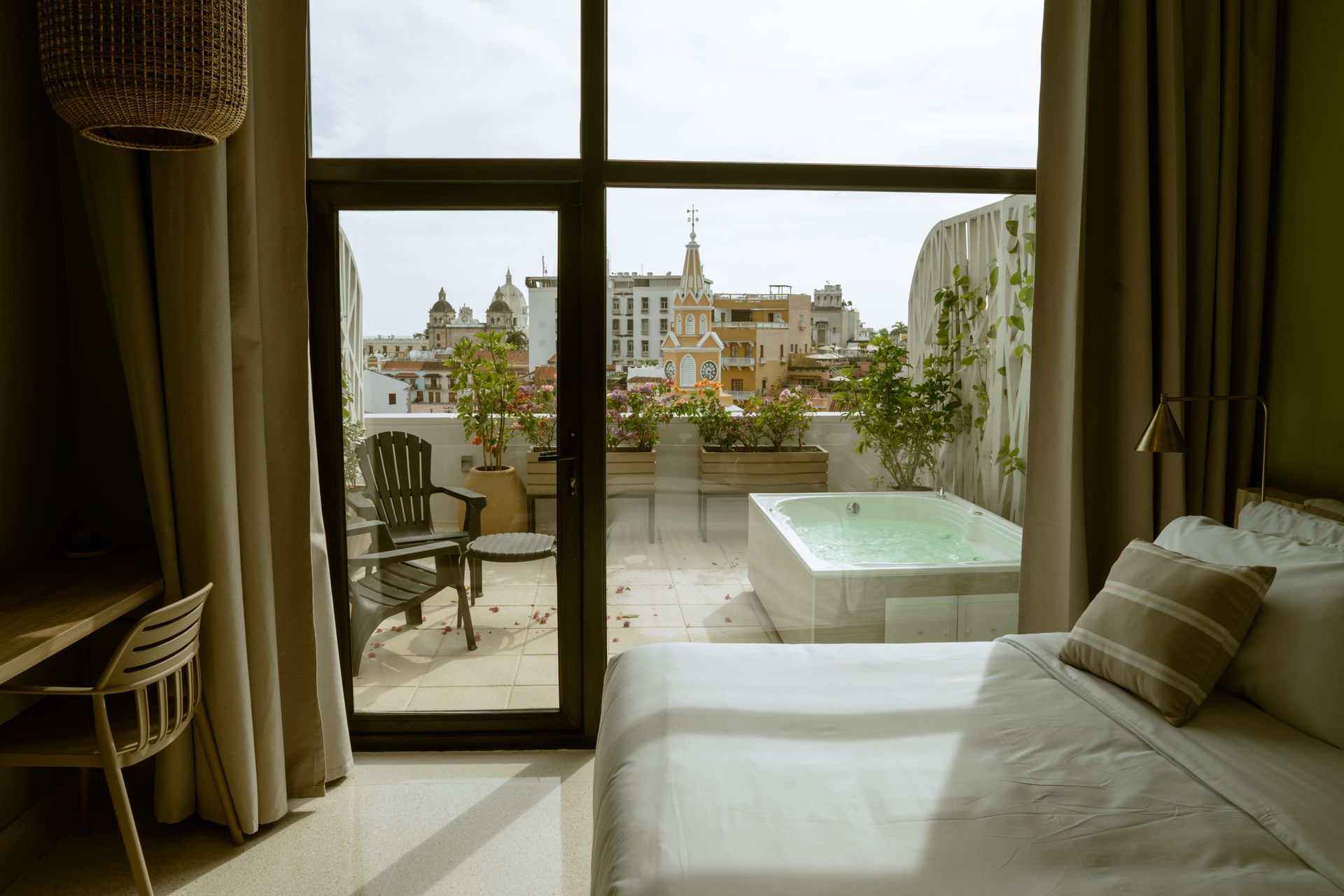 Una habitación de hotel con cama, escritorio, sillas y un jacuzzi en el balcón.