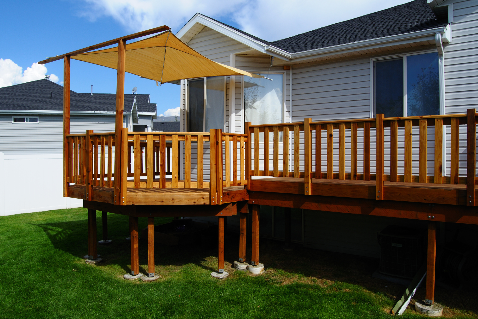 A photo of a deck installed on a house in Minnesota. The Deck is roughly 4 feet off the ground and has a railing. Along with the railing, the deck also has a portion covered with a canopy sheet.