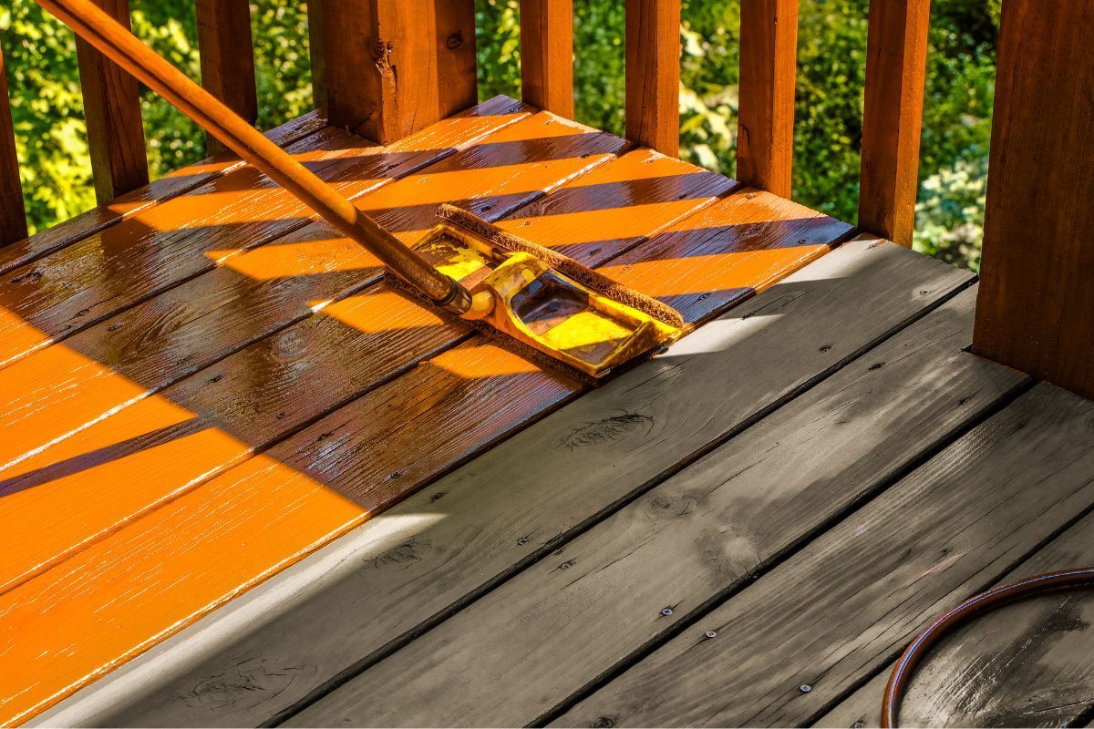 Staining a wooden deck with a bright orange tint in St. Paul, MN.