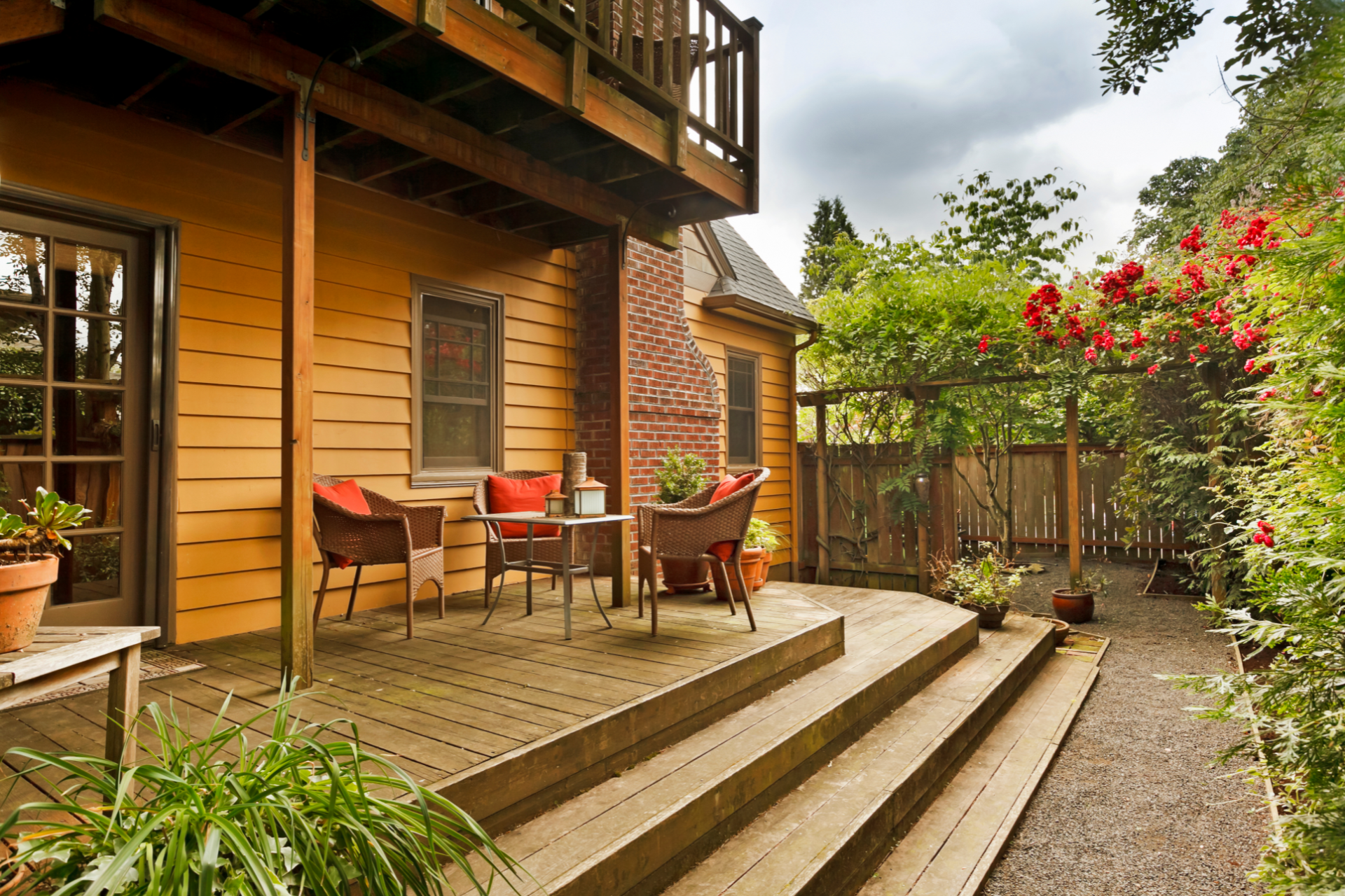 A photo of a deck installed in the backyard of a house. At the top of the photo, you can see a second level deck that is only accessible from inside the house. Underneath that deck is another ground-level deck that connects the house's sliding door to the patio and grass.