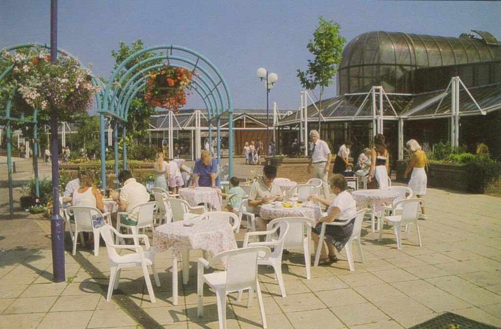 A group of people are sitting at tables outside on a sunny day