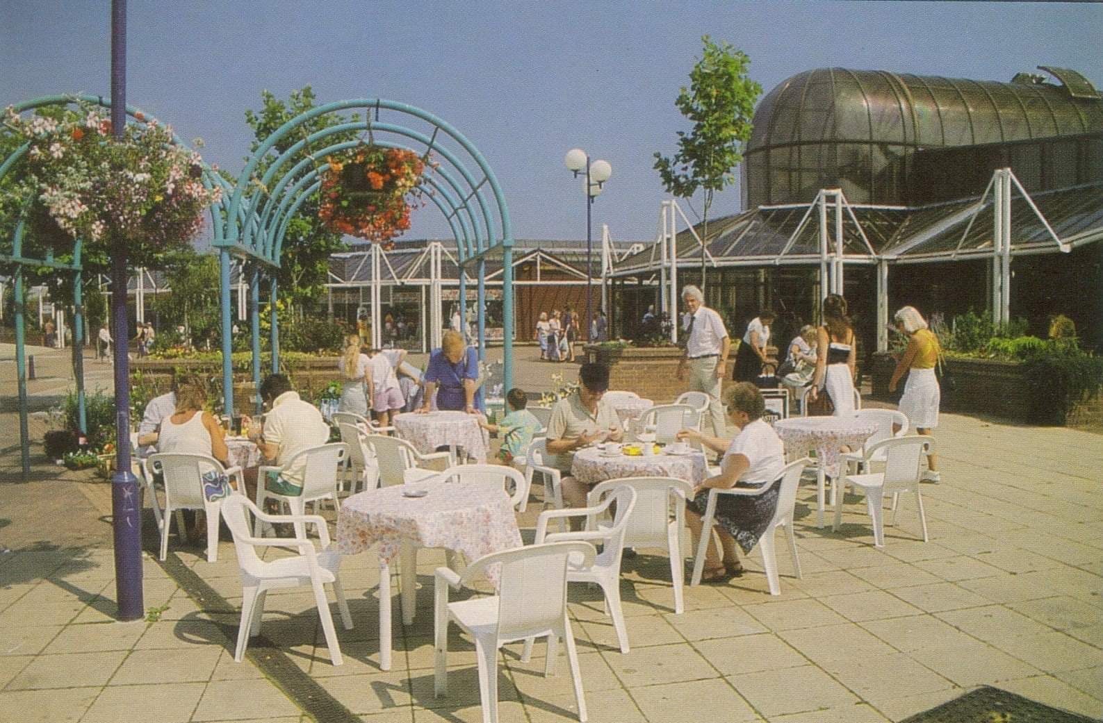 A group of people are sitting at tables in a park