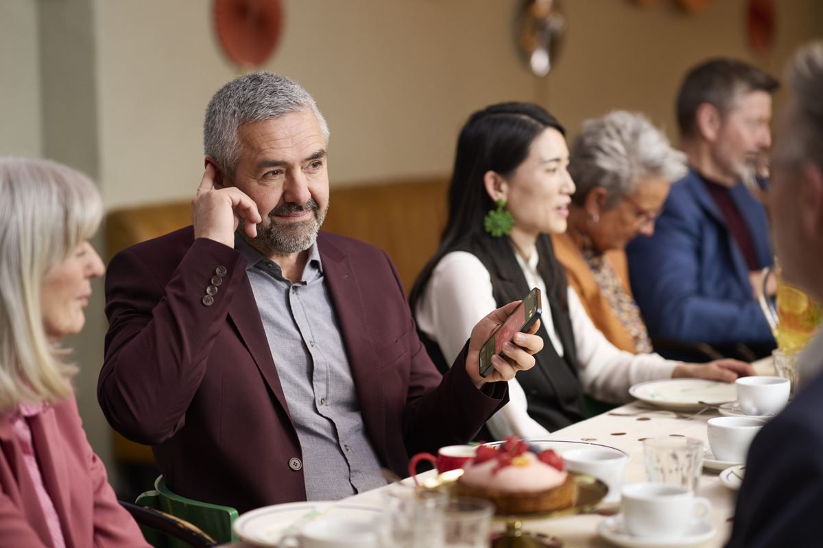 A group of people are sitting at a table talking on cell phones.