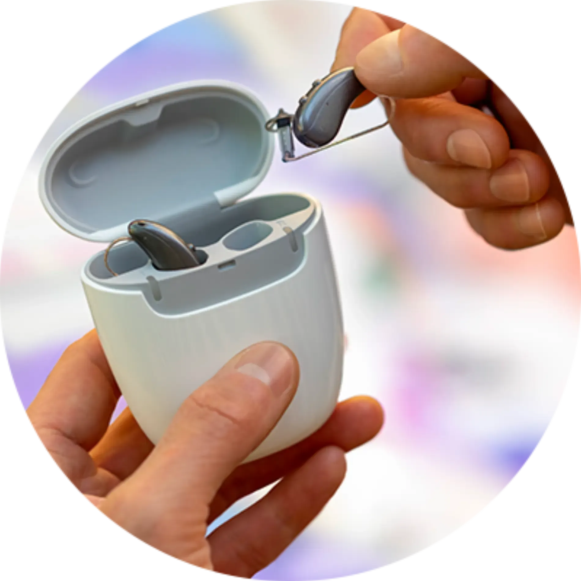 A person is holding a pair of hearing aids in a case