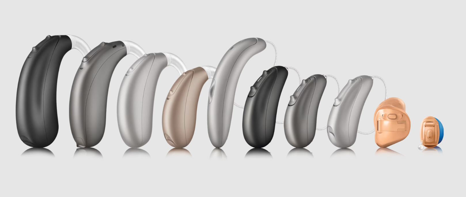 A row of hearing aids of different sizes and colors are lined up in a row.