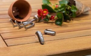 A pair of hearing aids are sitting on a wooden table next to a potted plant.