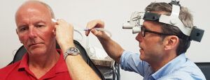 A man is getting his ears examined by a doctor.