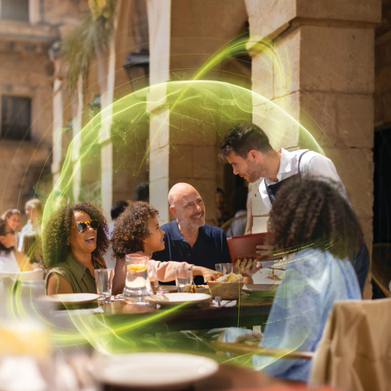 A group of people are sitting at a table in a restaurant talking to a waiter.