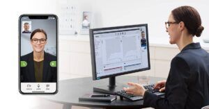 A woman is sitting at a desk talking to a man on a video call.