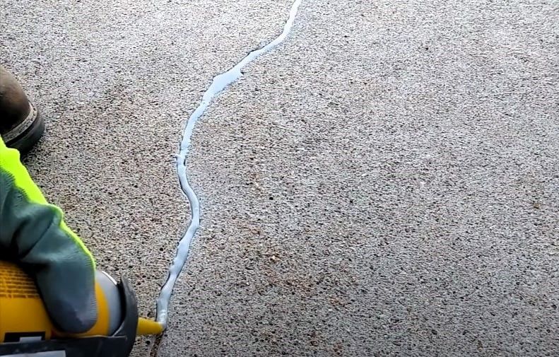 A person applying sealant to a crack in concrete.