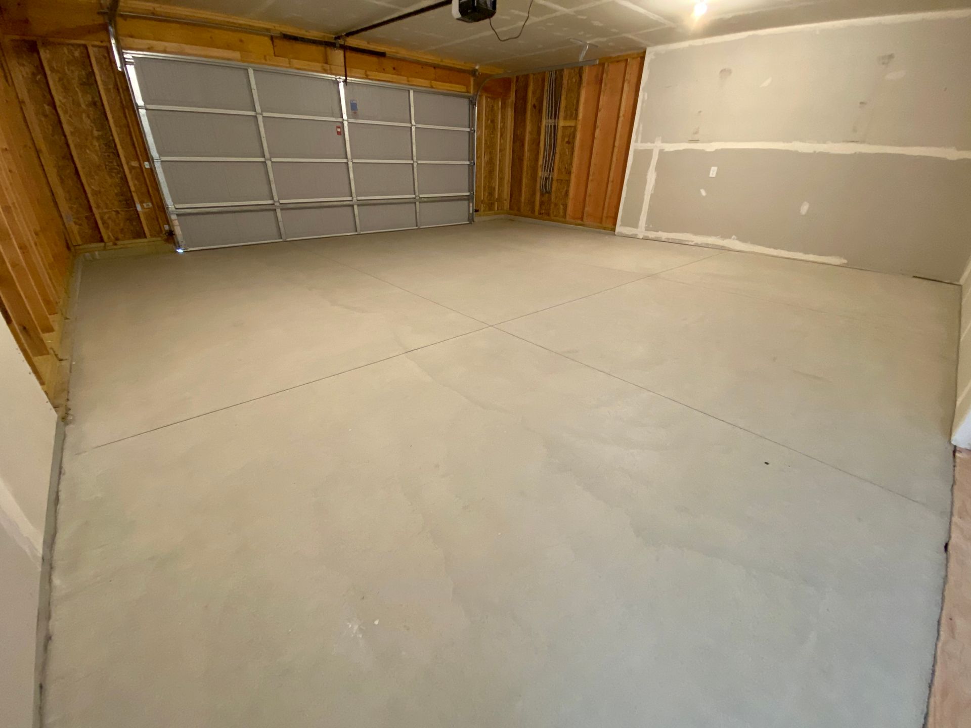 An empty garage with a garage door and a concrete floor.