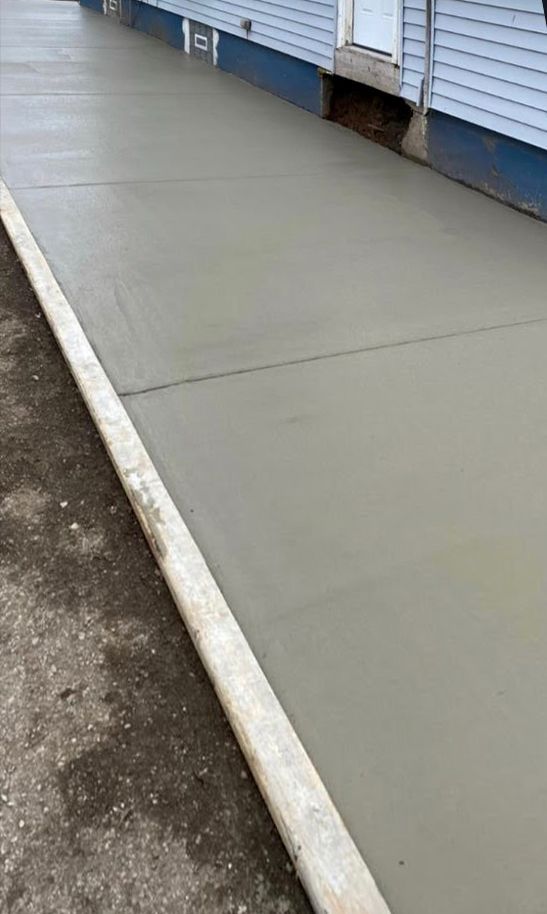 A concrete sidewalk is being built in front of a house.