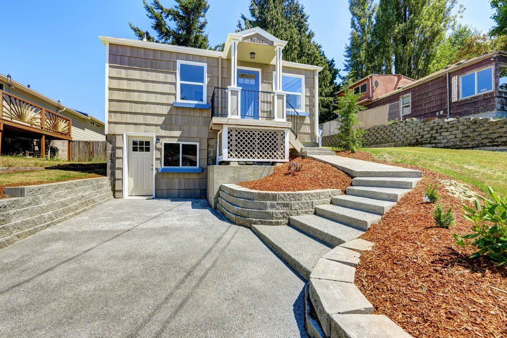 A house with a concrete driveway and stairs leading up to it.
