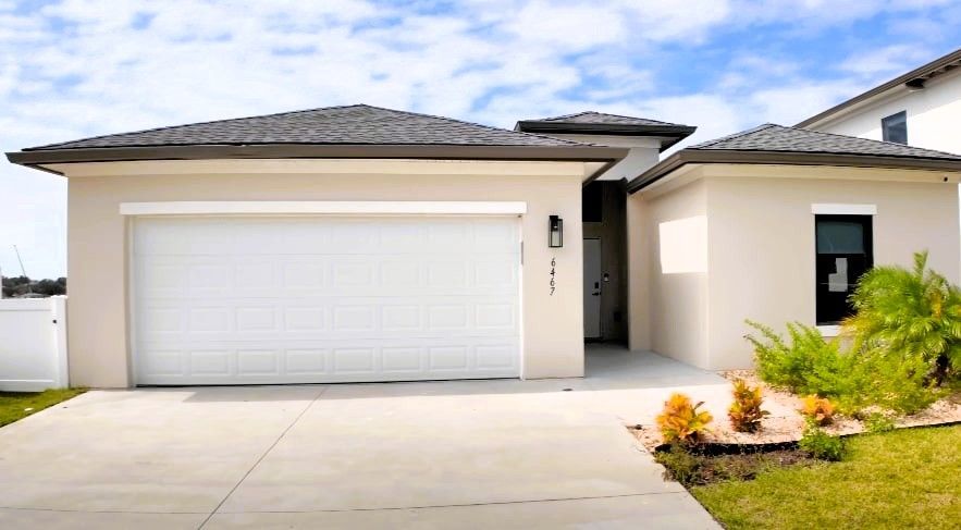 Modern house with residential concrete driveway under a partly cloudy sky.