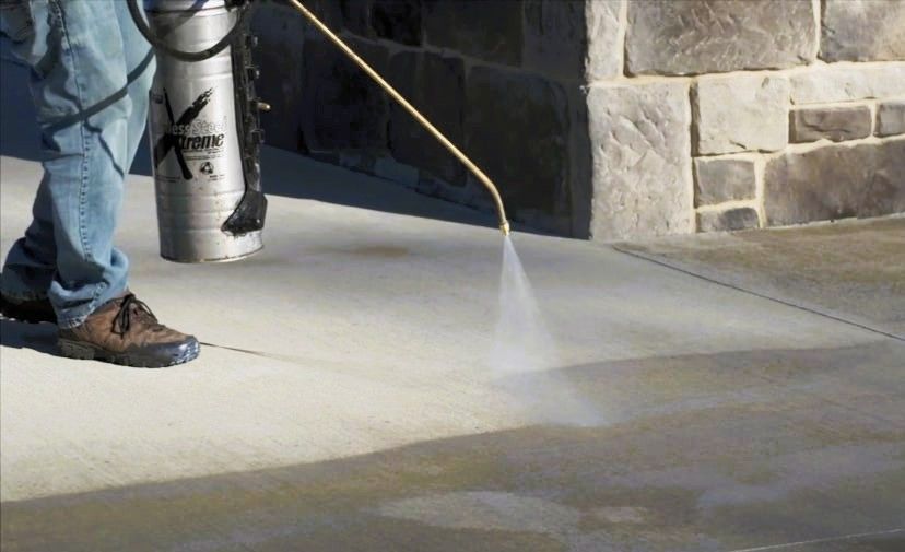 A person sealing a concrete driveway for winter preparation