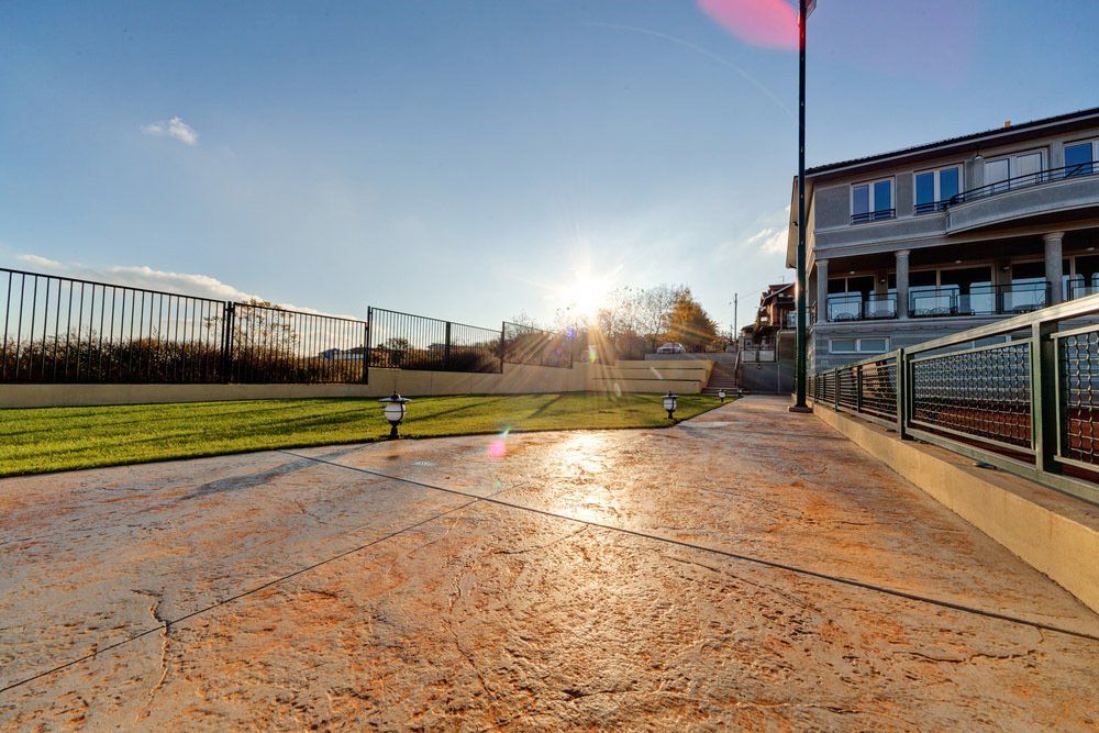 The sun is shining on a stained concrete walkway in front of a large building.