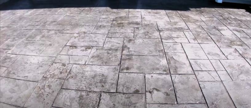 Weathered stamped concrete patio with worn stone tile patterns