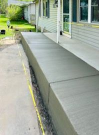 A concrete porch is being built on the side of a house.