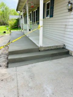 A concrete porch with steps being built in front of a house.
