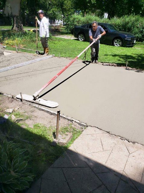 Two men are working on a concrete driveway.